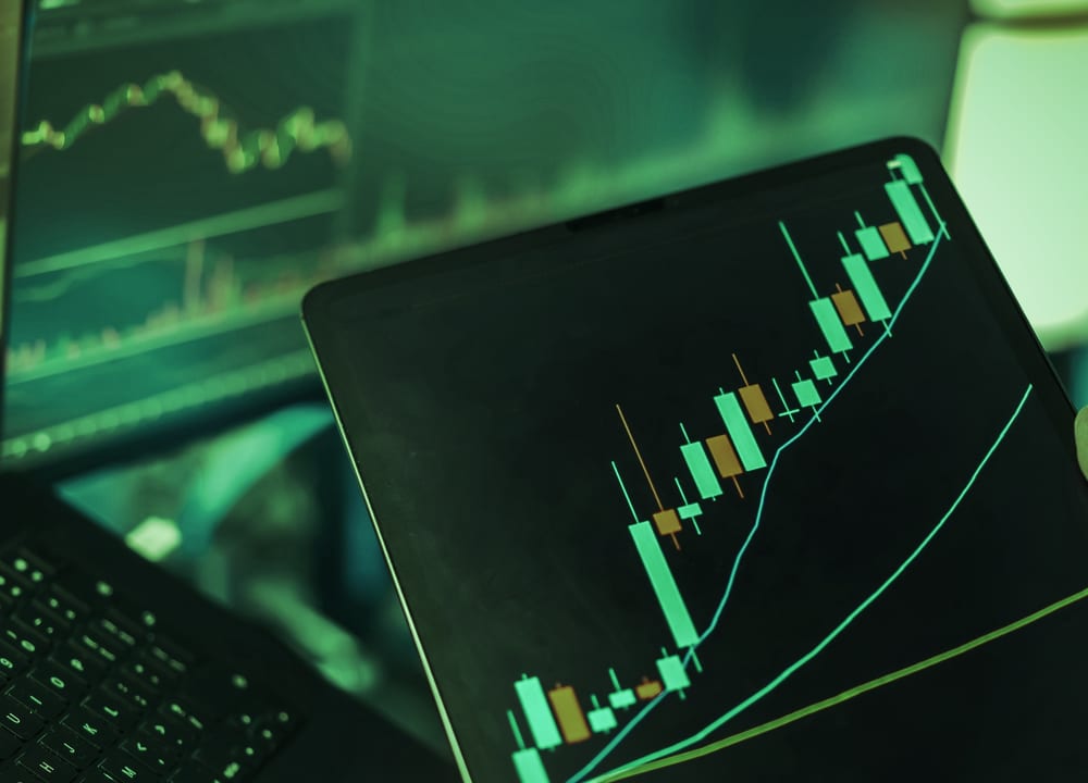 Tablet showing a rising candlestick chart with moving averages